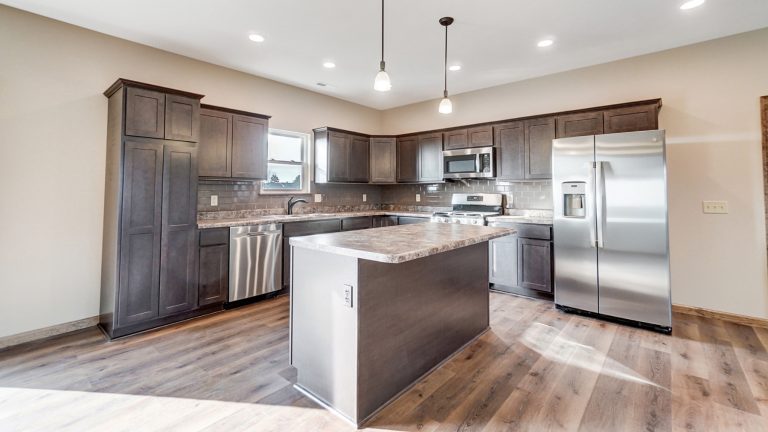 Kitchen with dark-colored wood cabinets, center island, and stainless steel appliances.